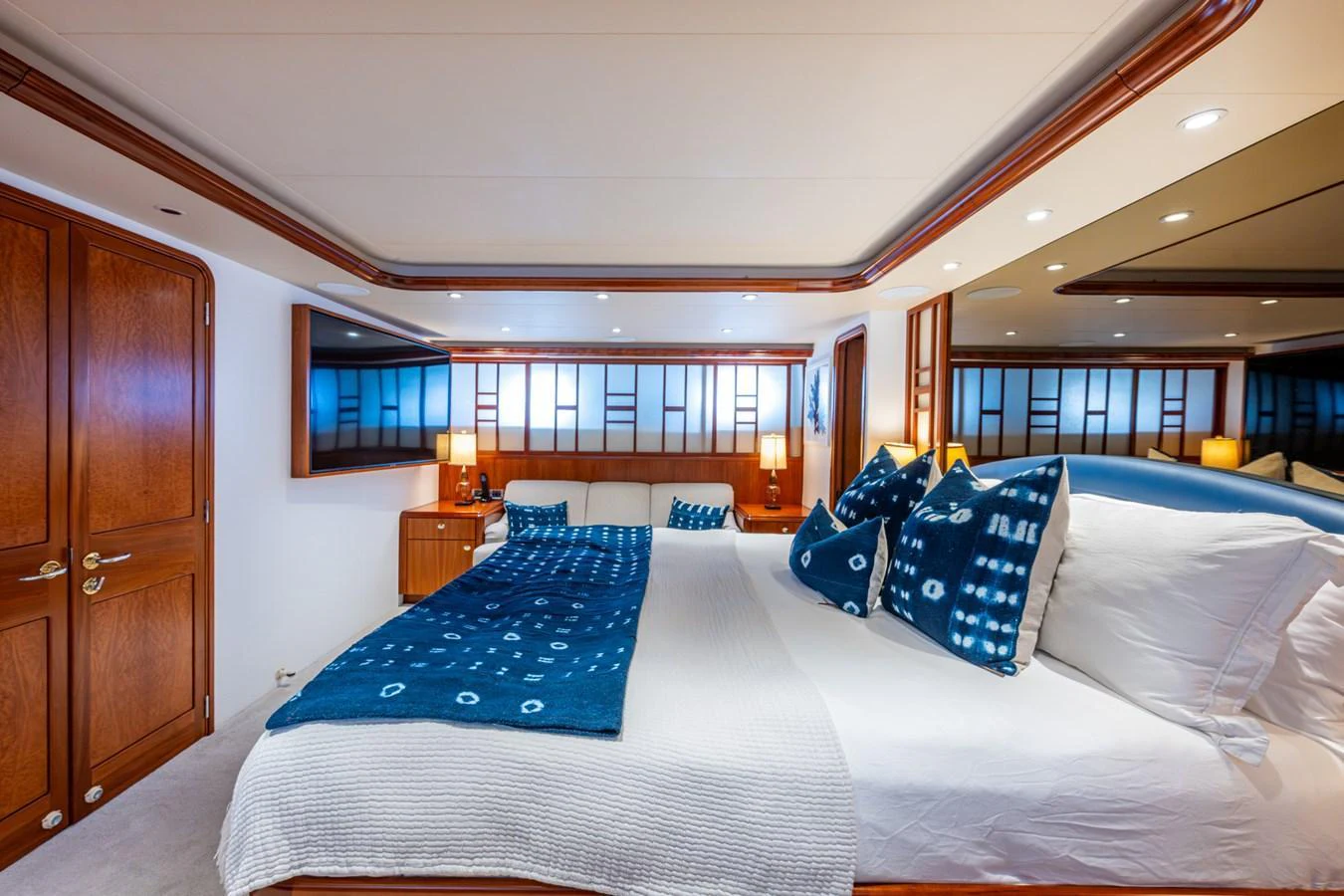 The stateroom features a luxurious bed with elegant blue and white decor, complemented by warm wooden accents. aboard LILA CUY Yacht for Sale