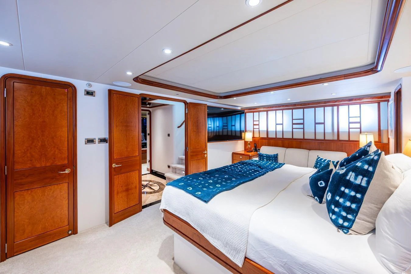 The master stateroom features a spacious bed with elegant wooden accents and modern lighting. aboard LILA CUY Yacht for Sale