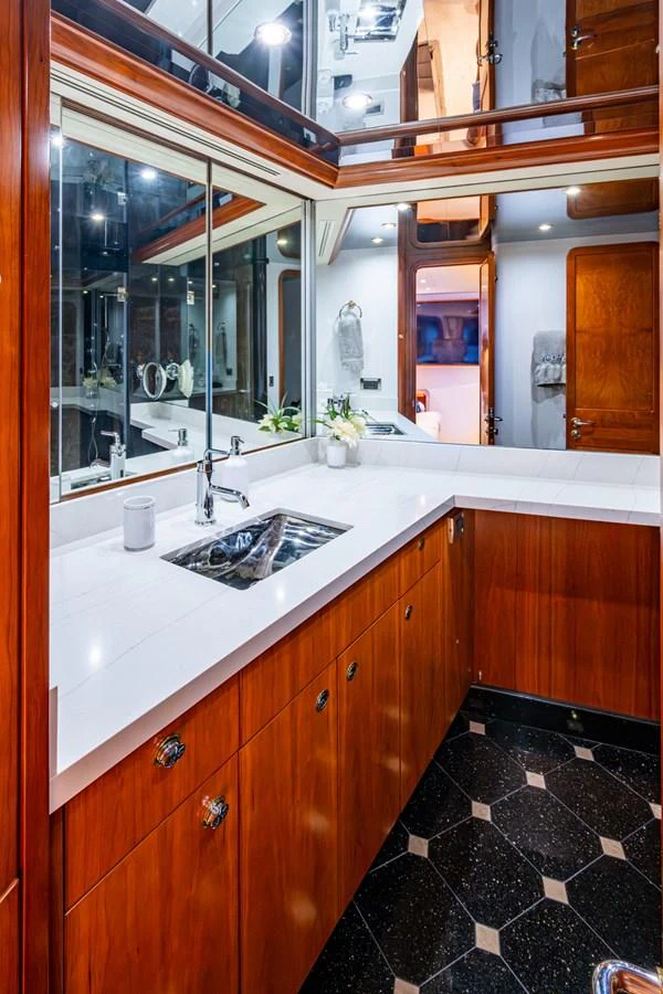The yacht's bathroom features elegant wood cabinetry, a sleek countertop, and modern fixtures. aboard LILA CUY Yacht for Sale