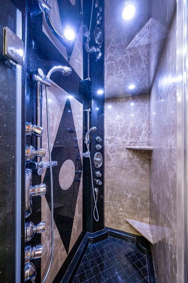The yacht features a luxurious shower with elegant marble walls and multiple showerheads. aboard LILA CUY Yacht for Sale