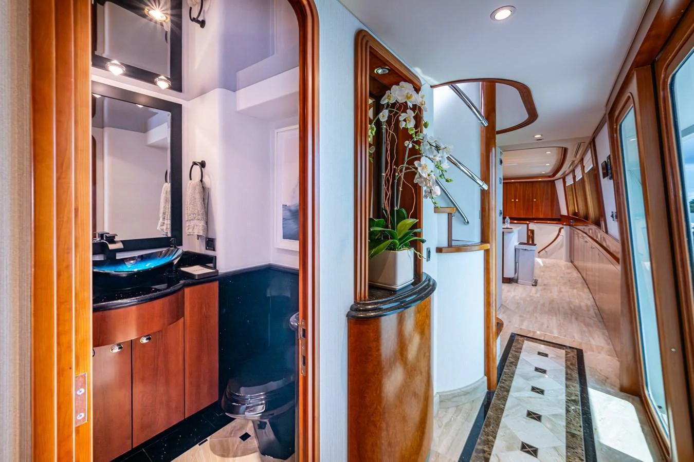 A luxurious yacht interior hallway with elegant wood finishes and a modern bathroom. aboard LILA CUY Yacht for Sale