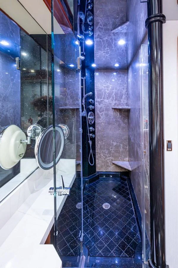 The yacht's bathroom features luxurious marble walls, a spacious shower area, and modern fixtures. aboard LILA CUY Yacht for Sale