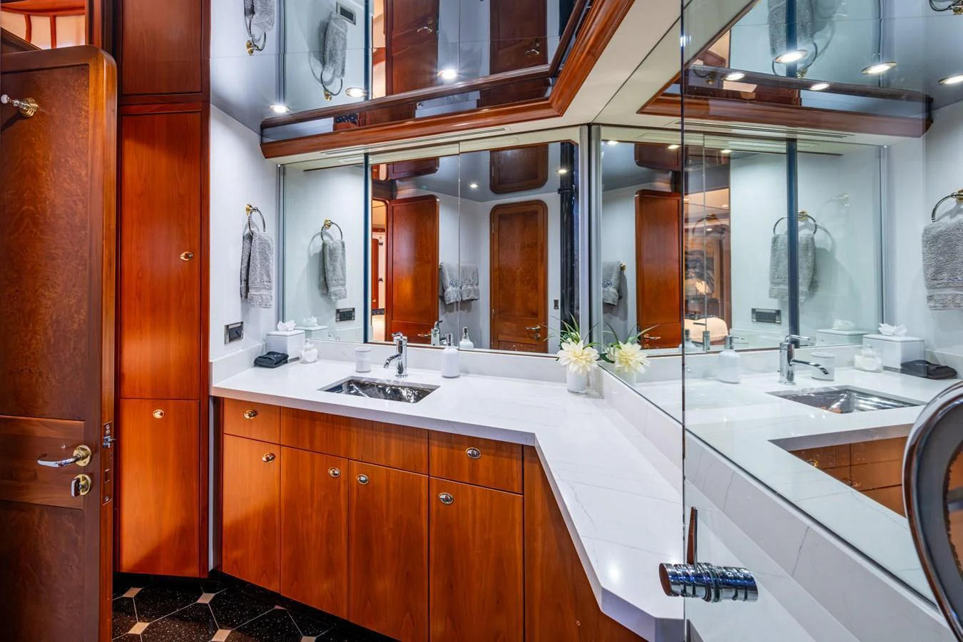 The yacht's bathroom features elegant wood cabinetry, a sleek countertop, and ample mirrors for a luxurious experience. aboard LILA CUY Yacht for Sale