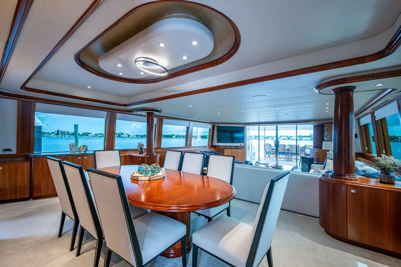 The yacht's dining area features a luxurious wooden table surrounded by comfortable seating, with panoramic windows offering stunning views. aboard LILA CUY Yacht for Sale