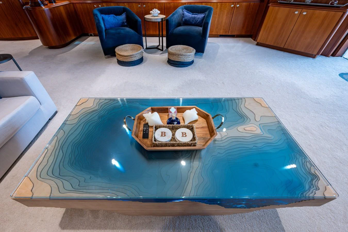 The yacht's interior features a stylish coffee table with a unique topographic design, complemented by plush seating and elegant wooden cabinetry. aboard LILA CUY Yacht for Sale