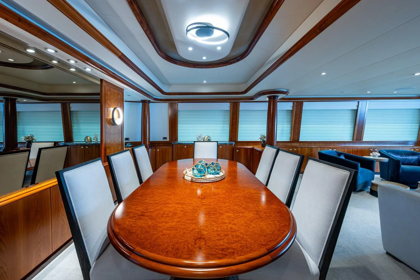 The yacht's dining area features a polished wooden table surrounded by elegant upholstered chairs, set in a spacious and well-lit environment. aboard LILA CUY Yacht for Sale