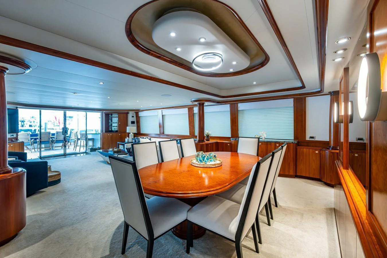 The yacht's dining area features a large wooden table with elegant seating, surrounded by luxurious finishes and ample natural light. aboard LILA CUY Yacht for Sale