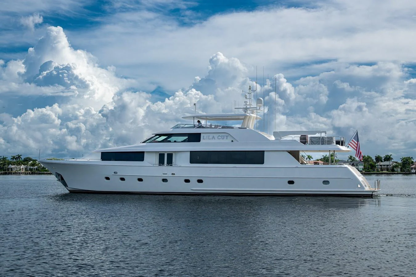A sleek and elegant yacht cruises gracefully on calm waters under a partly cloudy sky. aboard LILA CUY Yacht for Sale