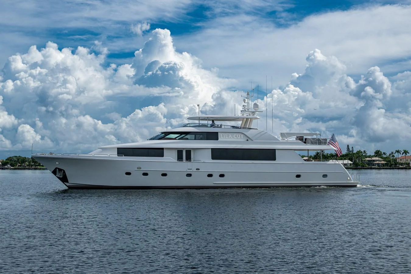 A sleek white yacht cruises gracefully on calm waters under a partly cloudy sky. aboard LILA CUY Yacht for Sale