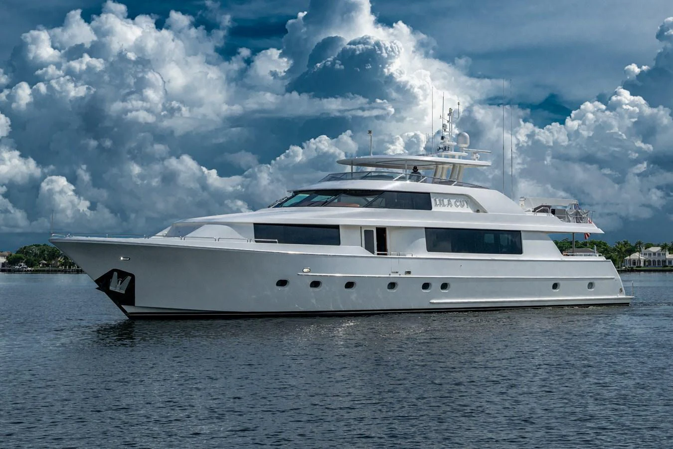 A luxurious yacht glides gracefully on calm waters under a dramatic sky. aboard LILA CUY Yacht for Sale