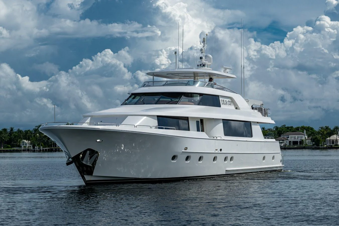 A sleek white yacht glides gracefully on calm waters under a partly cloudy sky. aboard LILA CUY Yacht for Sale