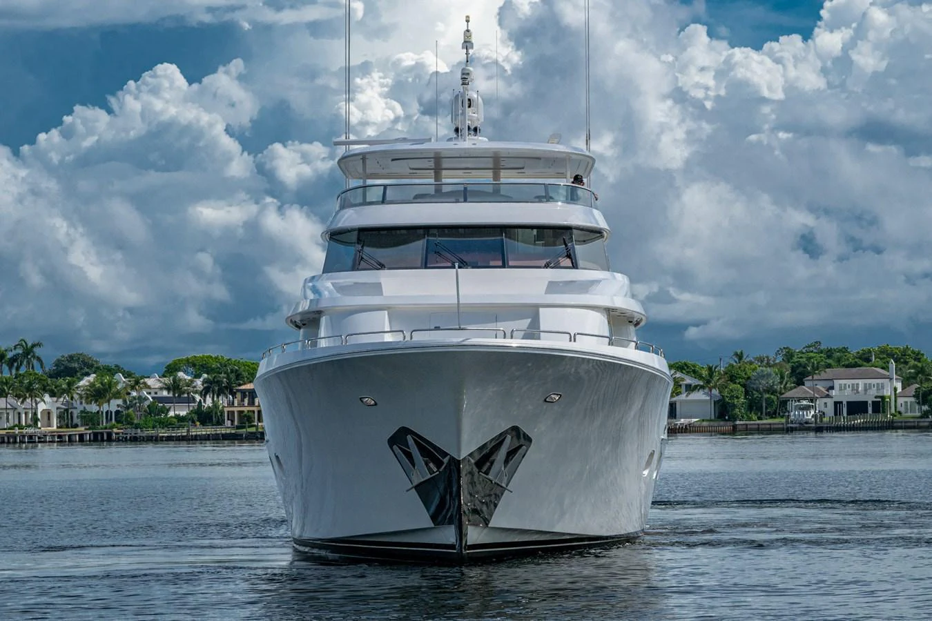 A stunning yacht is captured head-on, showcasing its sleek design against a backdrop of serene waters and a cloudy sky. aboard LILA CUY Yacht for Sale