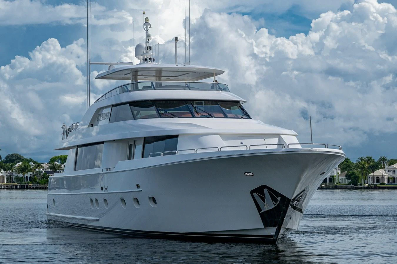 A luxurious yacht is anchored in calm waters with a backdrop of picturesque clouds and shoreline. aboard LILA CUY Yacht for Sale