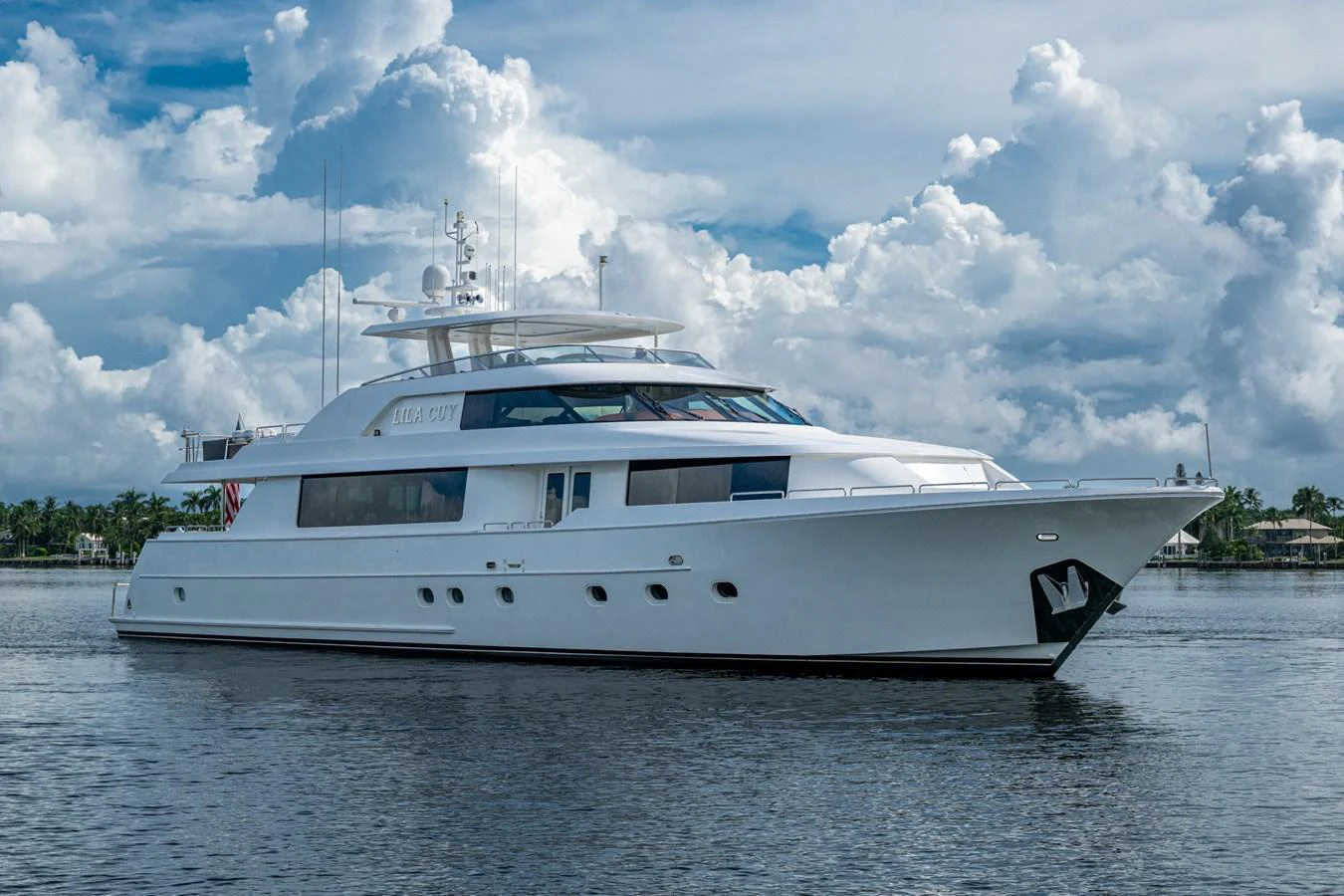 A sleek white yacht glides gracefully on calm waters under a partly cloudy sky. aboard LILA CUY Yacht for Sale