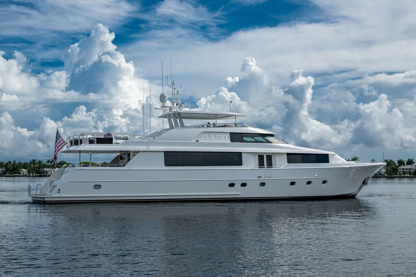 A sleek white yacht is anchored on calm waters under a partly cloudy sky. aboard LILA CUY Yacht for Sale