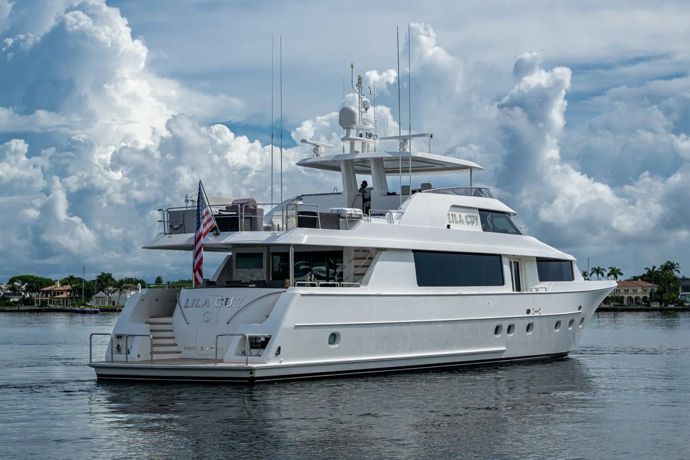 A sleek white yacht is anchored on calm waters under a partly cloudy sky. aboard LILA CUY Yacht for Sale