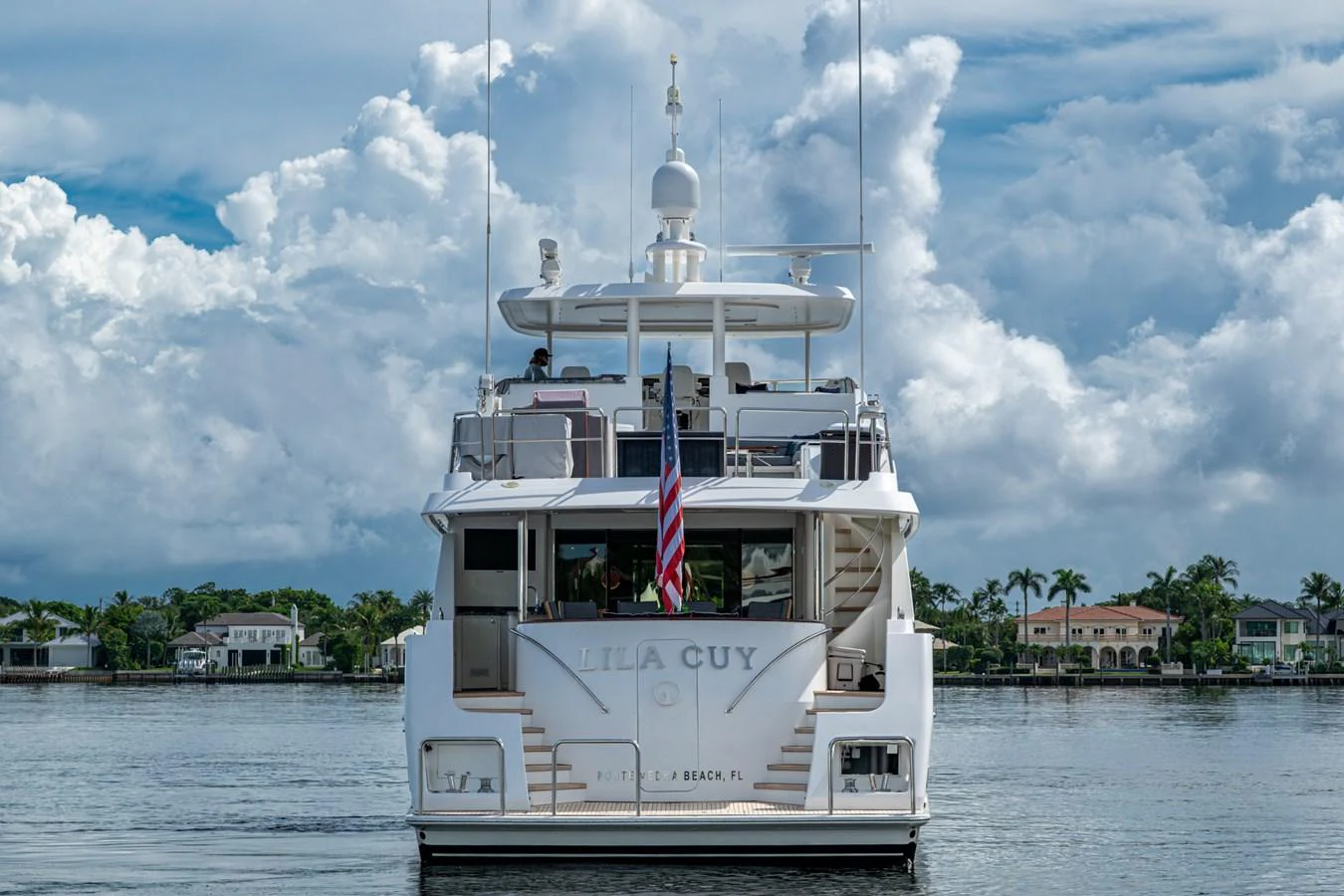The yacht is seen from the rear, showcasing its elegant design and serene waterfront setting. aboard LILA CUY Yacht for Sale