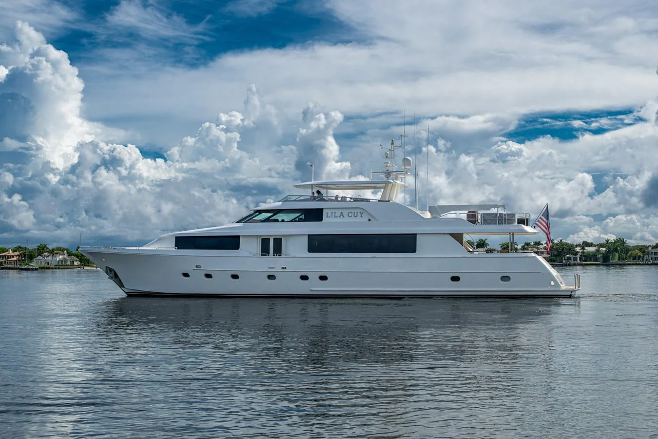 A sleek and elegant yacht glides gracefully on calm waters under a partly cloudy sky. aboard LILA CUY Yacht for Sale