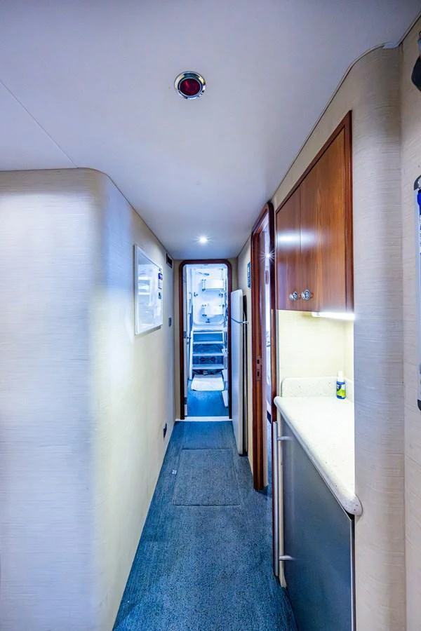 A narrow hallway with wooden cabinetry and a small kitchenette area leading to the yacht's interior. aboard LILA CUY Yacht for Sale