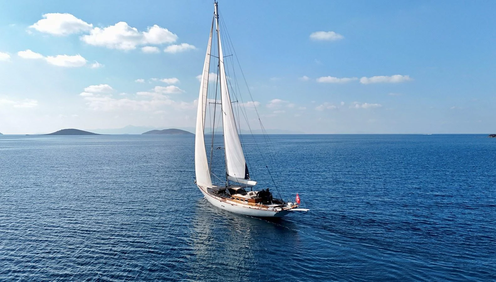A stunning sailing yacht glides gracefully on calm blue waters under a clear sky. aboard PORTOBELLO Yacht for Sale