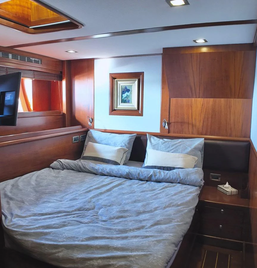 This cozy stateroom features a comfortable bed with elegant wooden paneling and modern lighting. aboard PORTOBELLO Yacht for Sale
