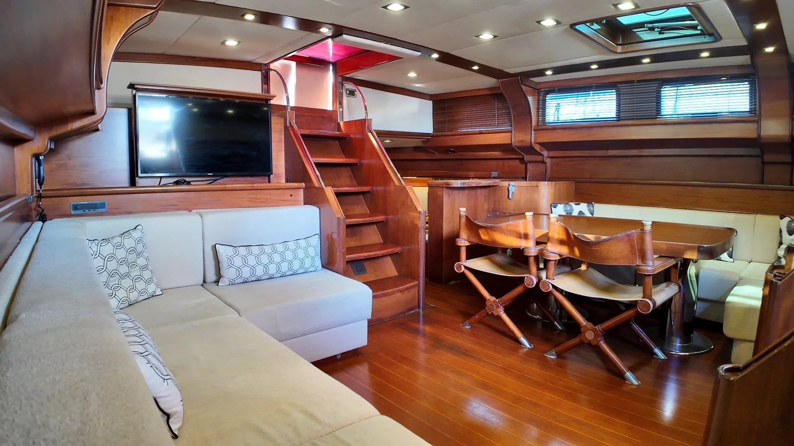 The yacht's salon features a cozy seating area, dining table, and wooden finishes. aboard PORTOBELLO Yacht for Sale