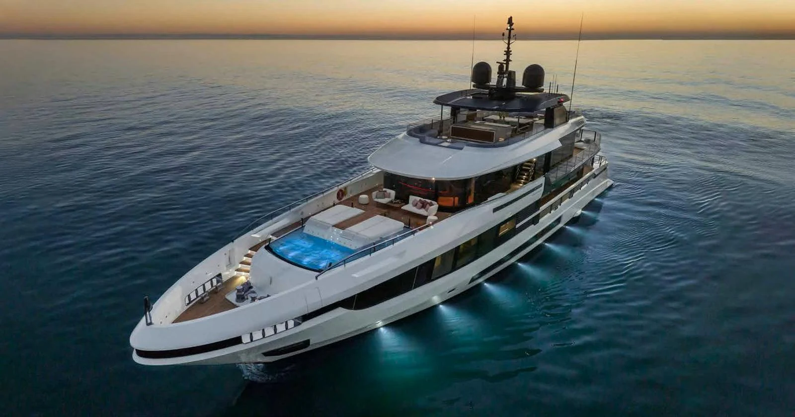 A sleek and modern yacht cruising at dusk with elegant lighting and a spacious deck. aboard MANGUSTA OCEANO 44, #8 Yacht for Sale