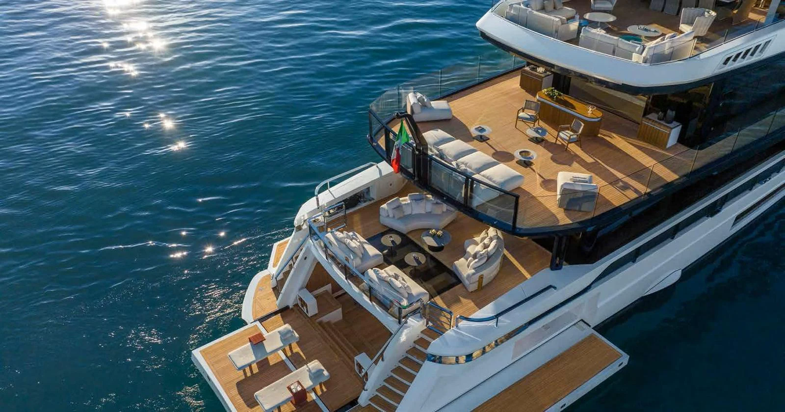 The yacht's aft deck showcases luxurious outdoor living spaces with elegant seating and dining areas over calm waters. aboard MANGUSTA OCEANO 44, #8 Yacht for Sale