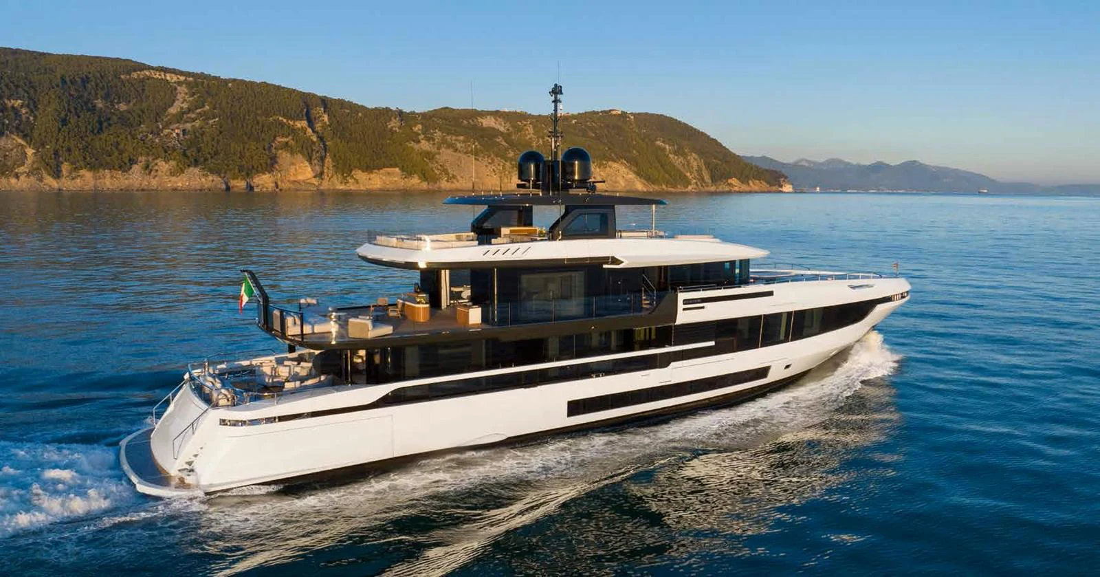 A sleek, modern yacht cruises through calm waters with a scenic coastline in the background. aboard MANGUSTA OCEANO 44, #8 Yacht for Sale