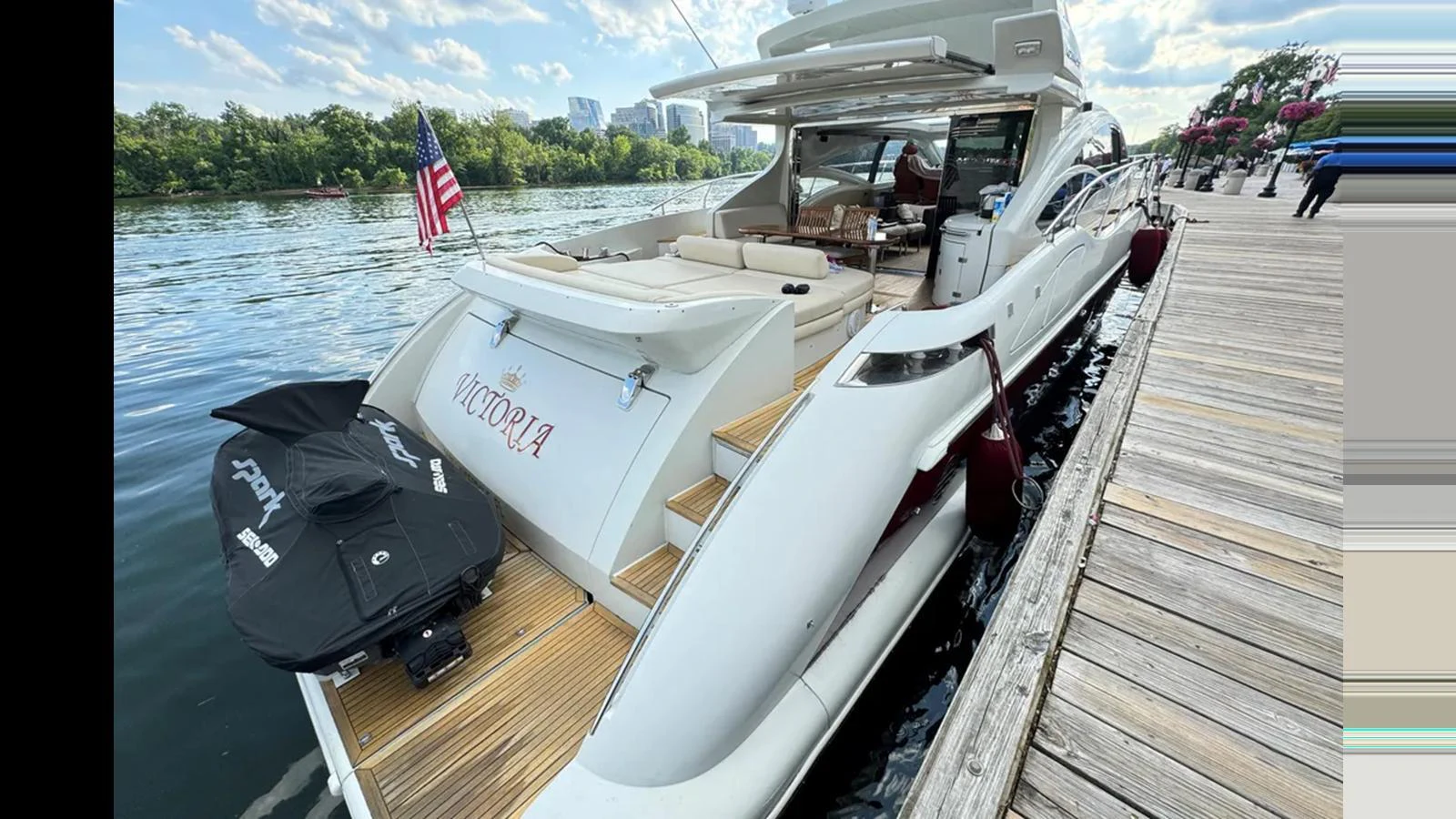 The yacht is docked, showcasing its spacious aft deck with a comfortable seating area and an American flag. aboard 2007 AZIMUT 68S Yacht for Sale