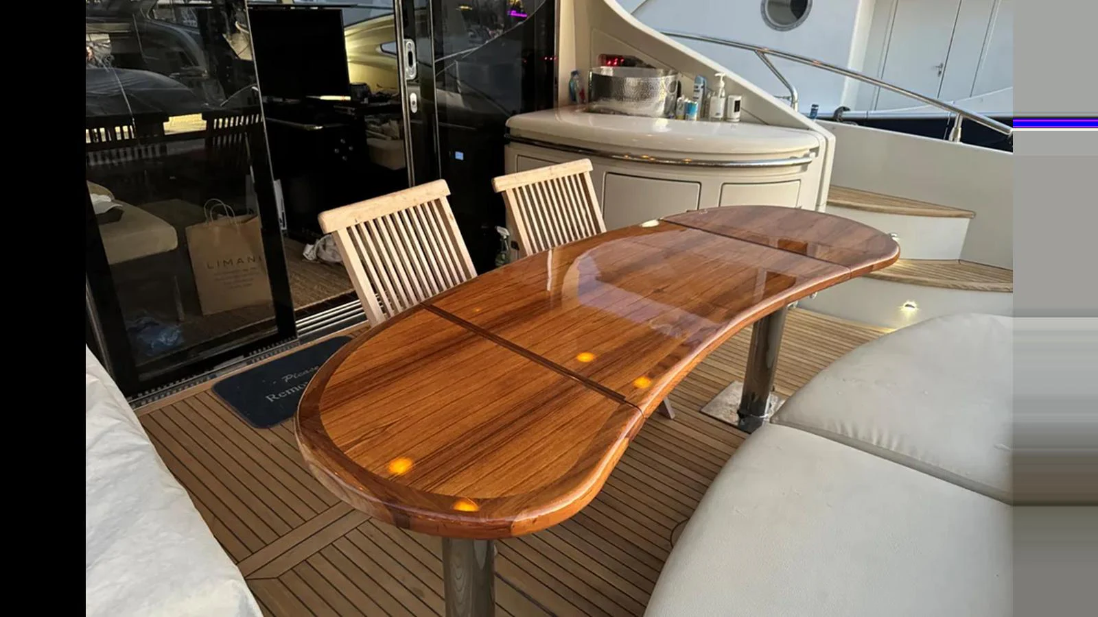 The aft deck features a polished wooden dining table with comfortable seating. aboard 2007 AZIMUT 68S Yacht for Sale