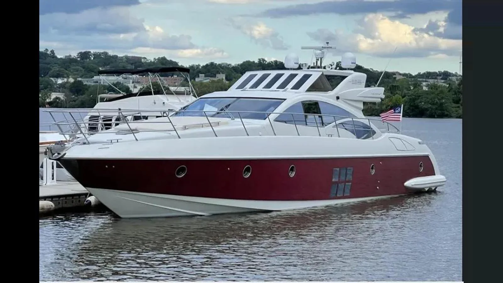 A sleek and modern yacht with a striking red and white exterior, docked in a serene marina. aboard 2007 AZIMUT 68S Yacht for Sale