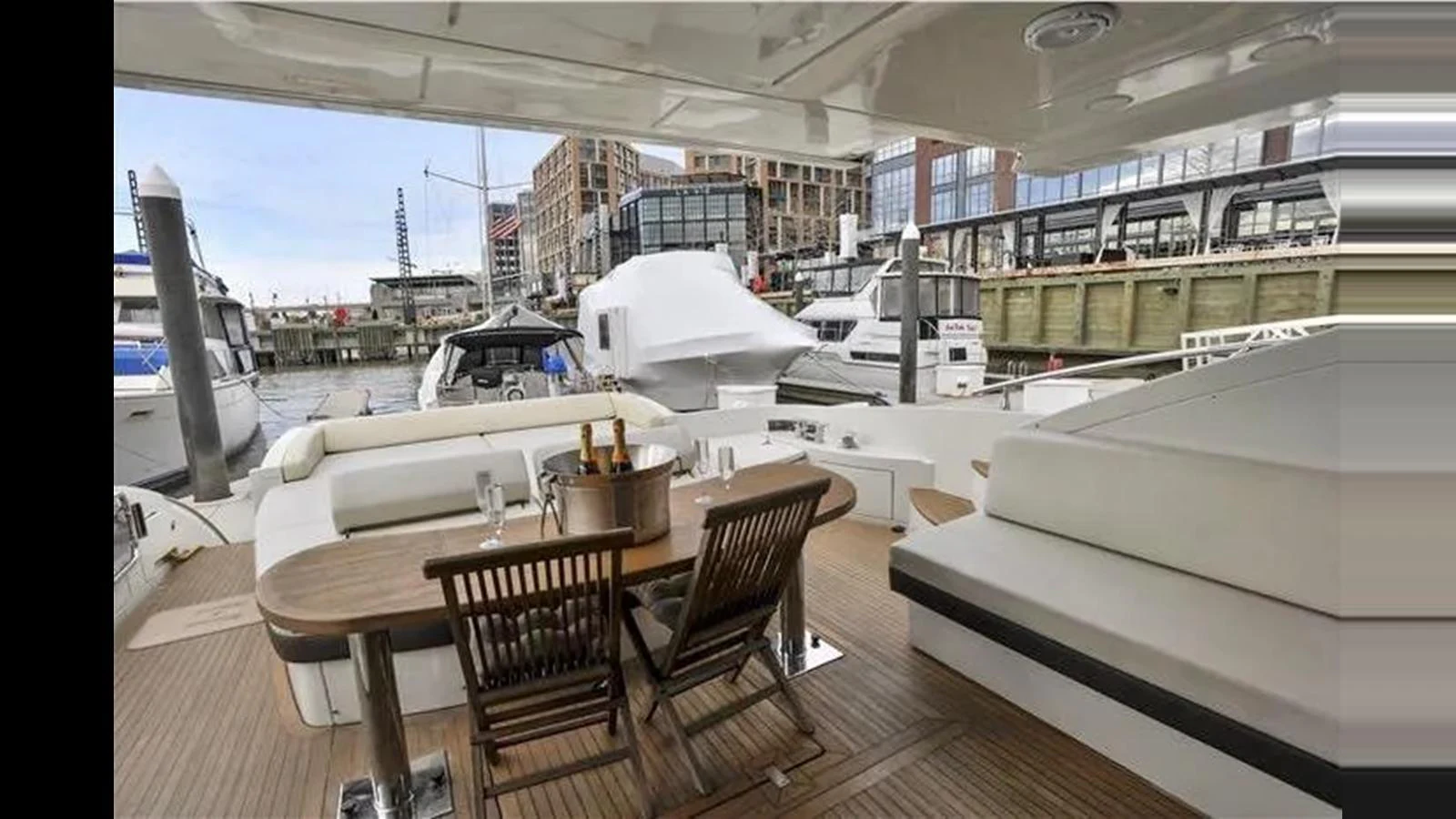The aft deck features a cozy dining area with a wooden table and cushioned seating, perfect for enjoying waterfront views. aboard 2007 AZIMUT 68S Yacht for Sale