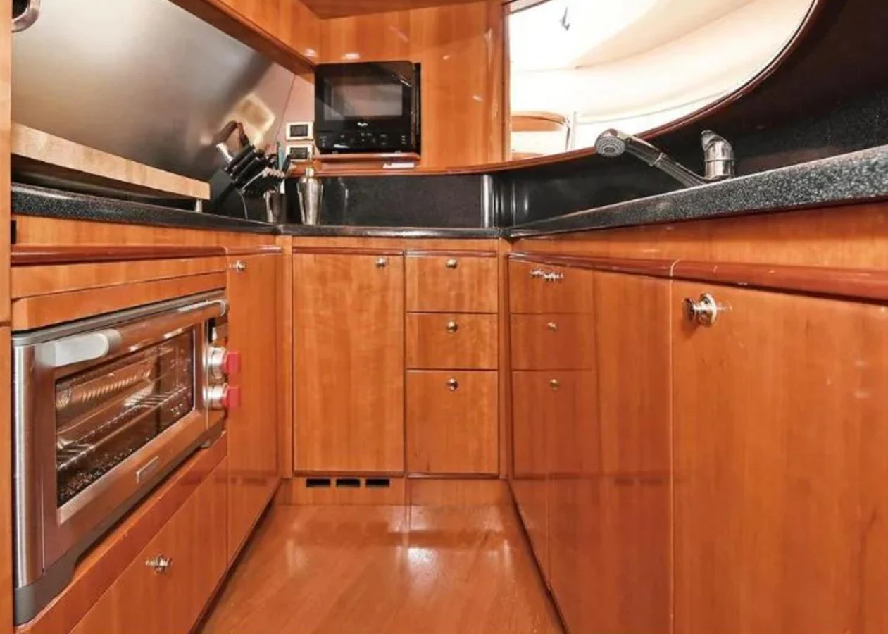 The yacht's galley features warm wood cabinetry and modern appliances, creating a cozy and functional space for meal preparation. aboard 2005 AZIMUT 68E Yacht for Sale