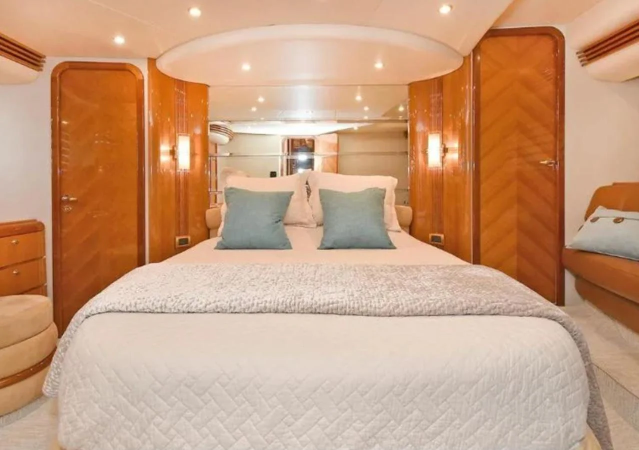 The master stateroom features a luxurious bed with plush pillows and elegant wood finishes. aboard 2005 AZIMUT 68E Yacht for Sale