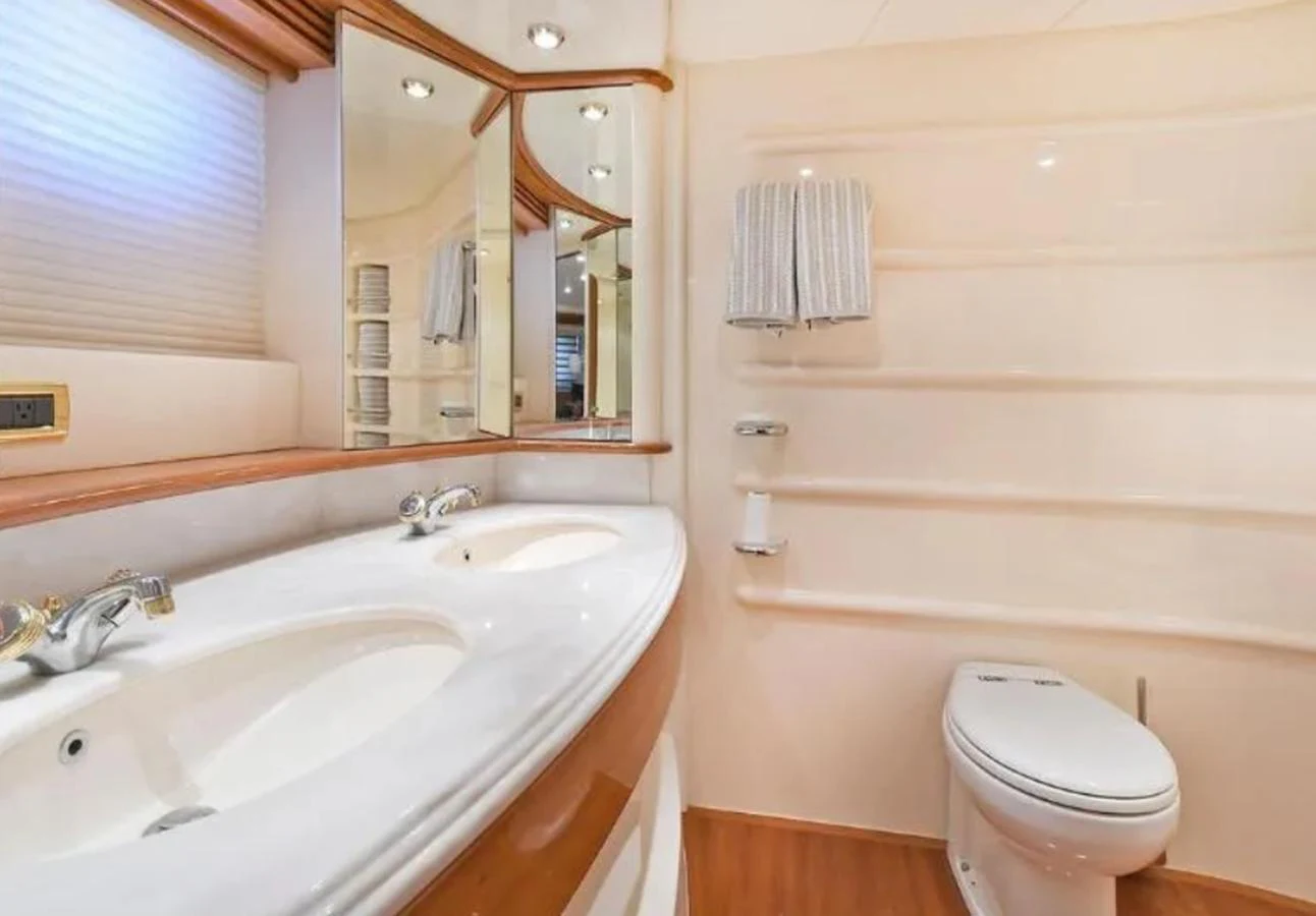 The yacht's bathroom features a double sink vanity, a toilet, and ample lighting. aboard 2005 AZIMUT 68E Yacht for Sale