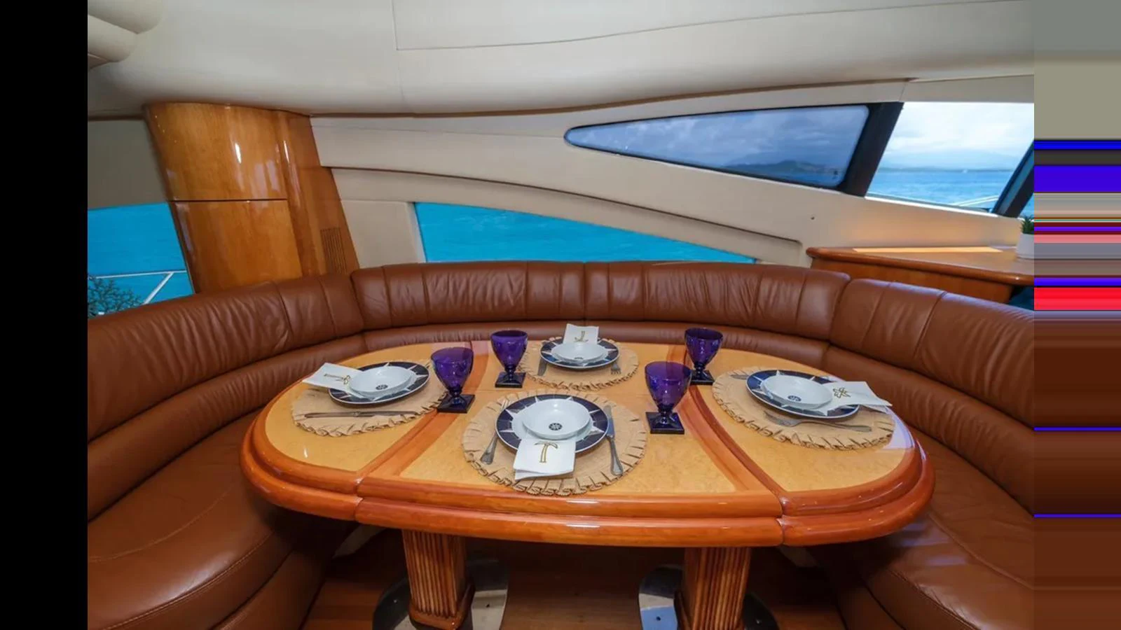 The yacht's dining area features a beautifully set table with a stunning ocean view through large windows. aboard 2005 AZIMUT 68E Yacht for Sale