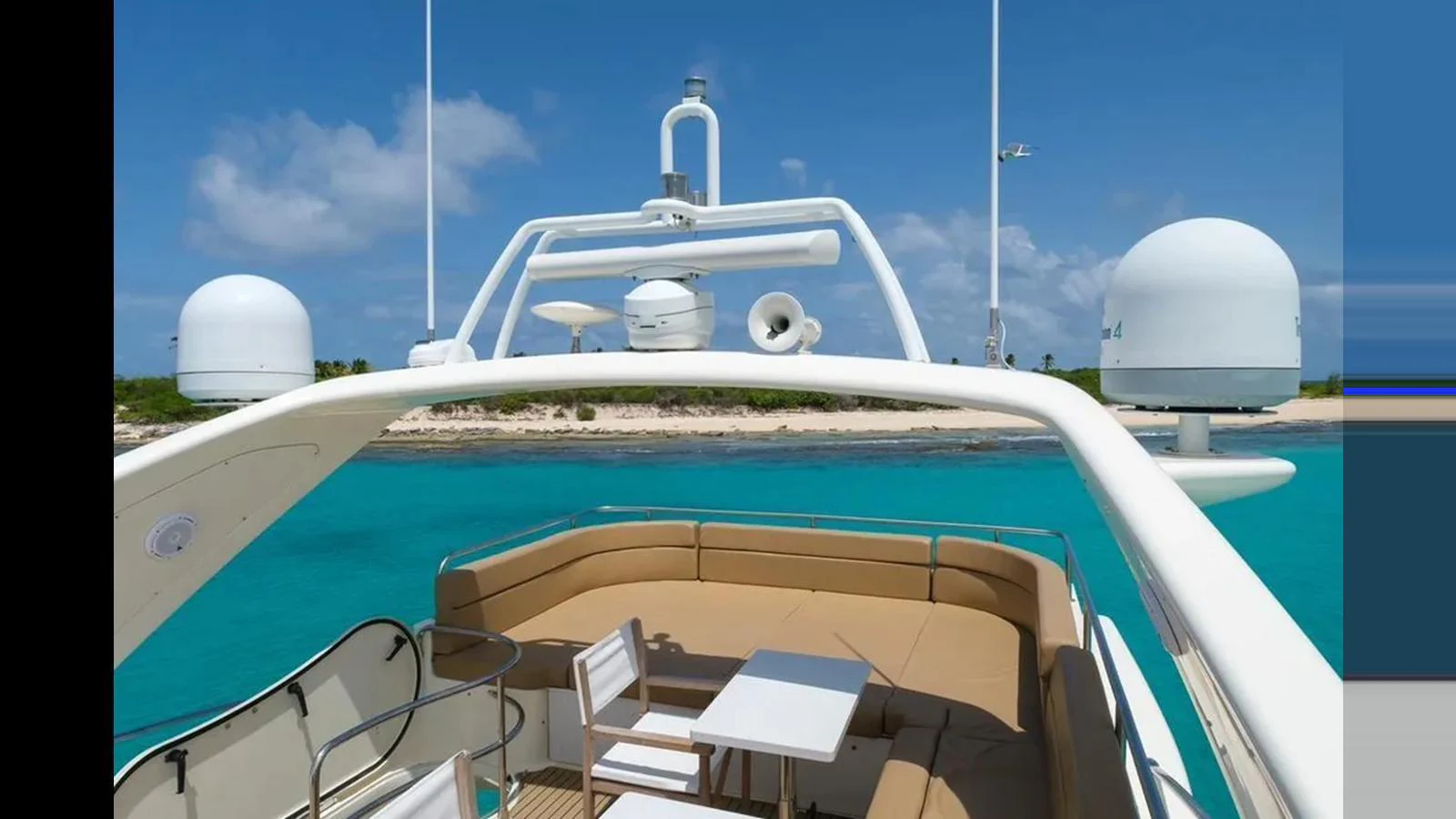 The flybridge offers a stunning view of the turquoise waters and is equipped with comfortable seating and a small dining area. aboard 2005 AZIMUT 68E Yacht for Sale