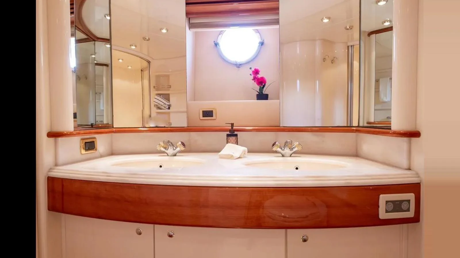 The yacht's bathroom features a double sink vanity with elegant fixtures and a porthole window. aboard 2005 AZIMUT 68E Yacht for Sale