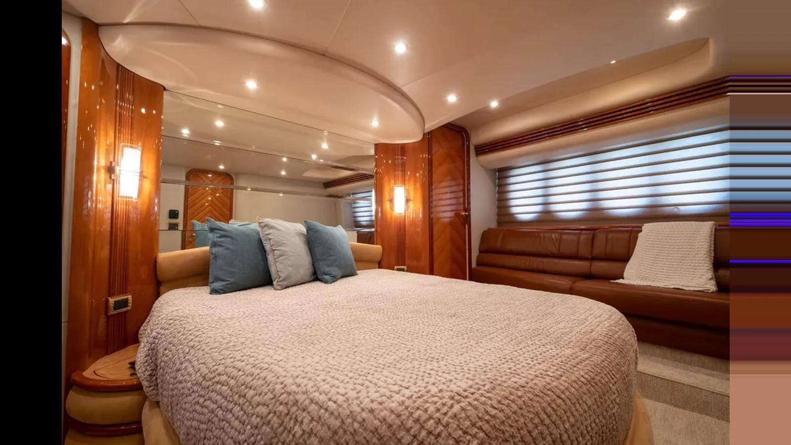 The master stateroom features a luxurious bed with plush bedding and elegant wood finishes. aboard 2005 AZIMUT 68E Yacht for Sale