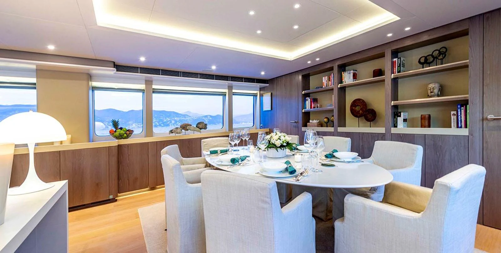 The yacht's dining area features a modern, elegant setting with a beautifully set table and ample natural light. aboard UNEXPECTED Yacht for Sale