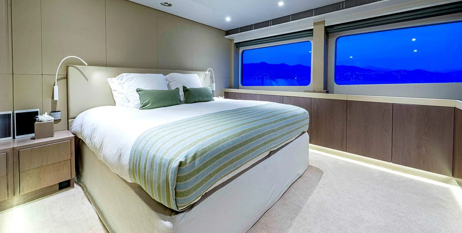 The stateroom features a luxurious bed with modern decor and large windows offering a serene view. aboard UNEXPECTED Yacht for Sale