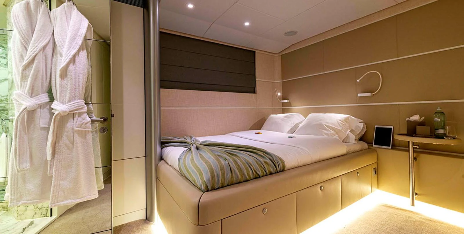 The stateroom features a cozy bed with elegant lighting and modern amenities. aboard UNEXPECTED Yacht for Sale