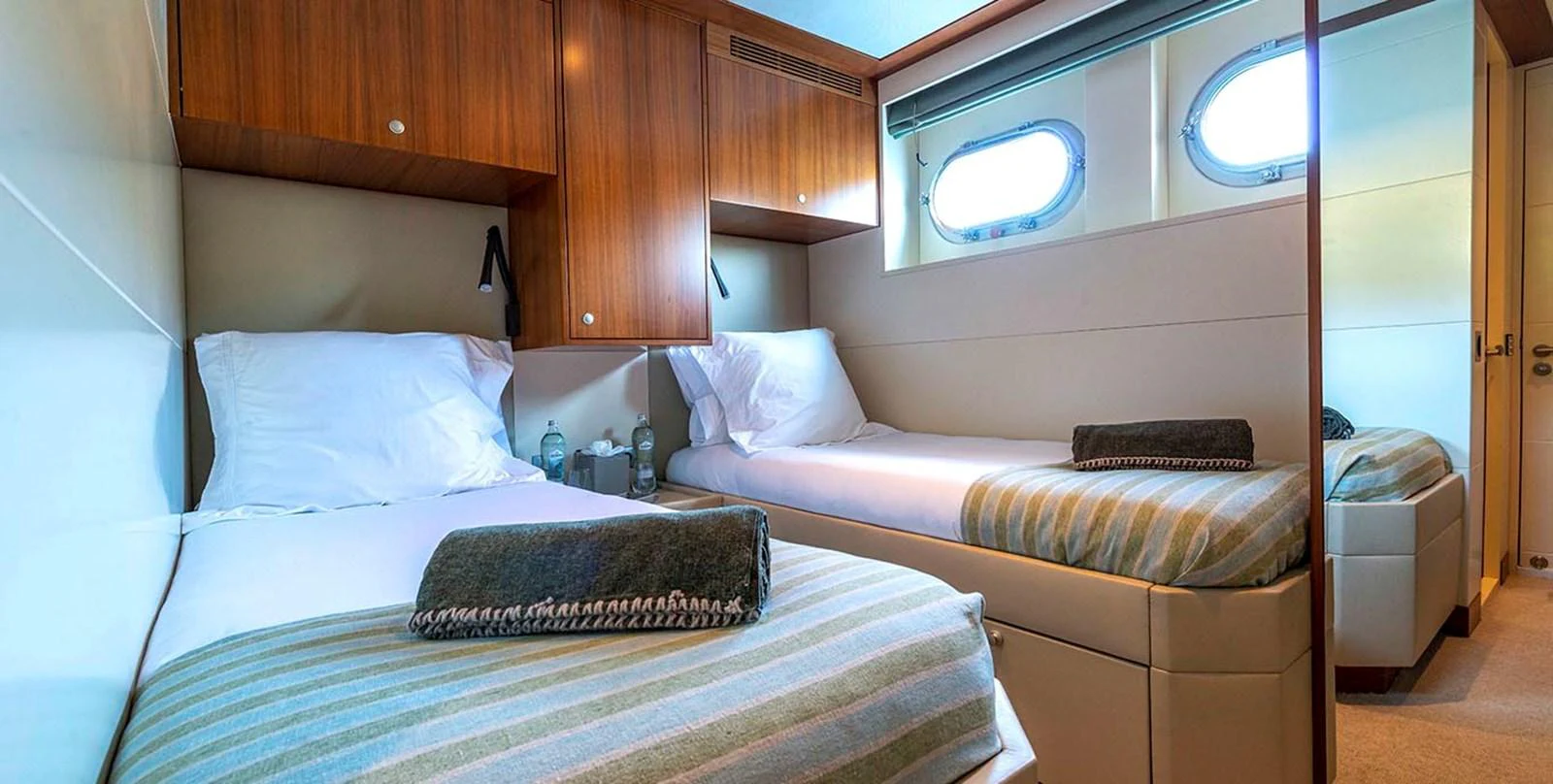 The twin stateroom offers a cozy and inviting space with two single beds and elegant wooden cabinetry. aboard UNEXPECTED Yacht for Sale