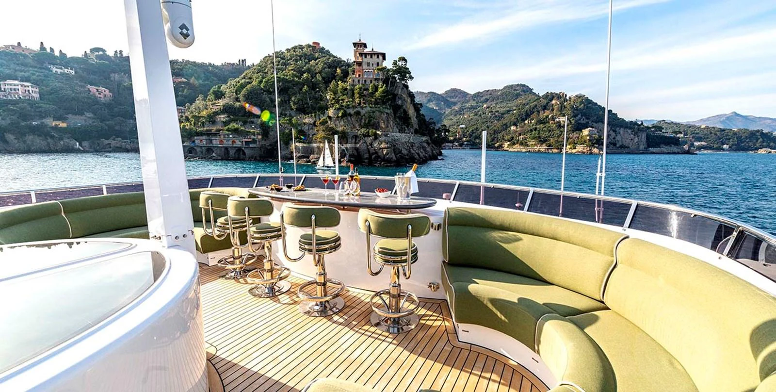 The aft deck features a spacious seating area with a bar, offering stunning views of the surrounding landscape. aboard UNEXPECTED Yacht for Sale