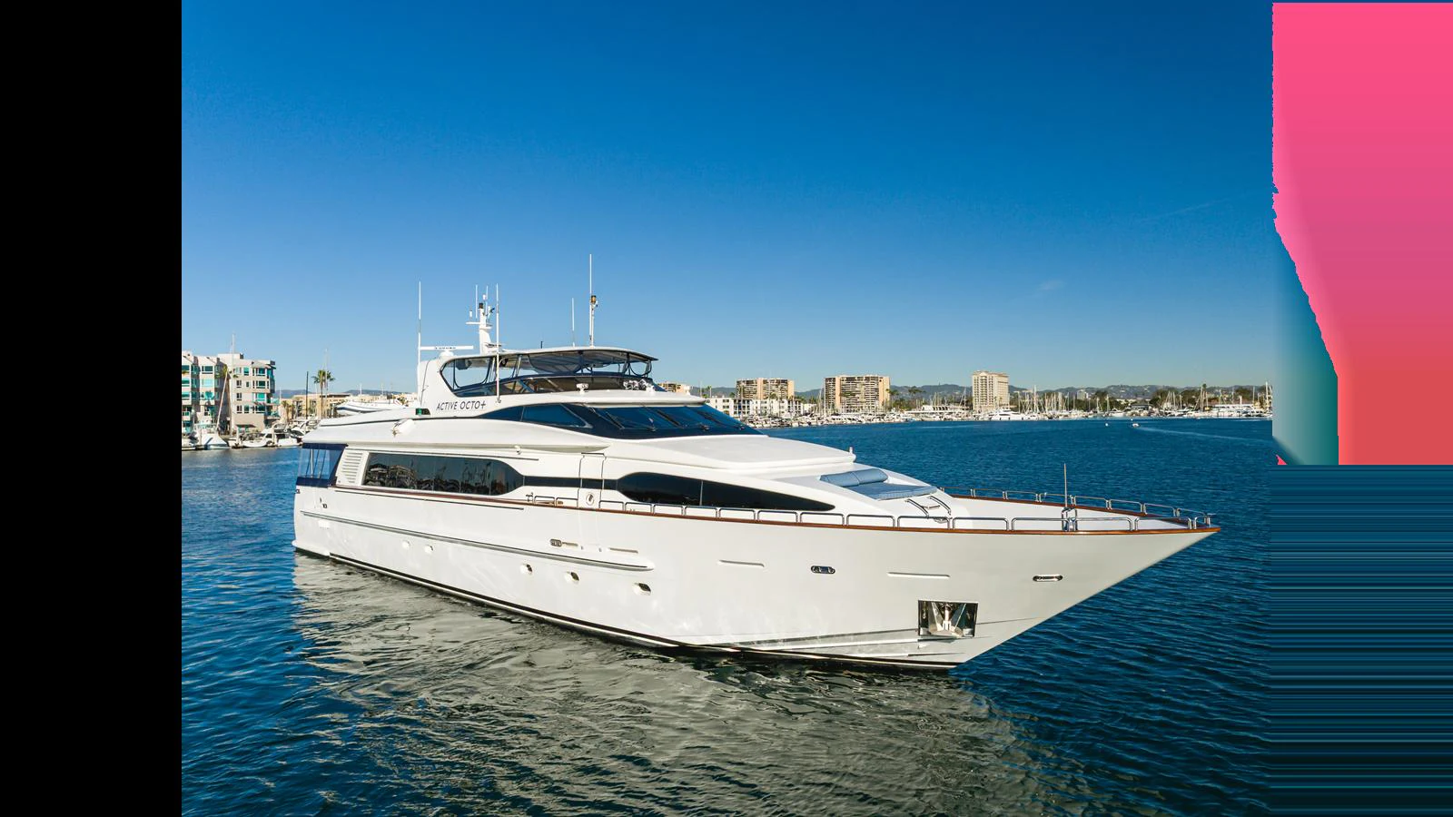 A sleek and modern yacht glides gracefully on the water with a cityscape in the background. aboard ACTIVE OCTO Yacht for Sale