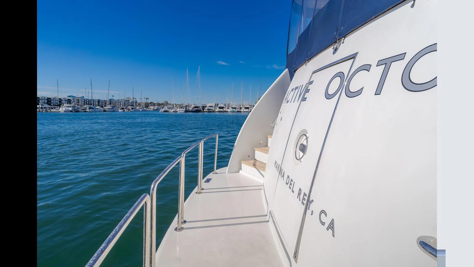 The yacht is docked in a serene marina with a clear blue sky overhead. aboard ACTIVE OCTO Yacht for Sale