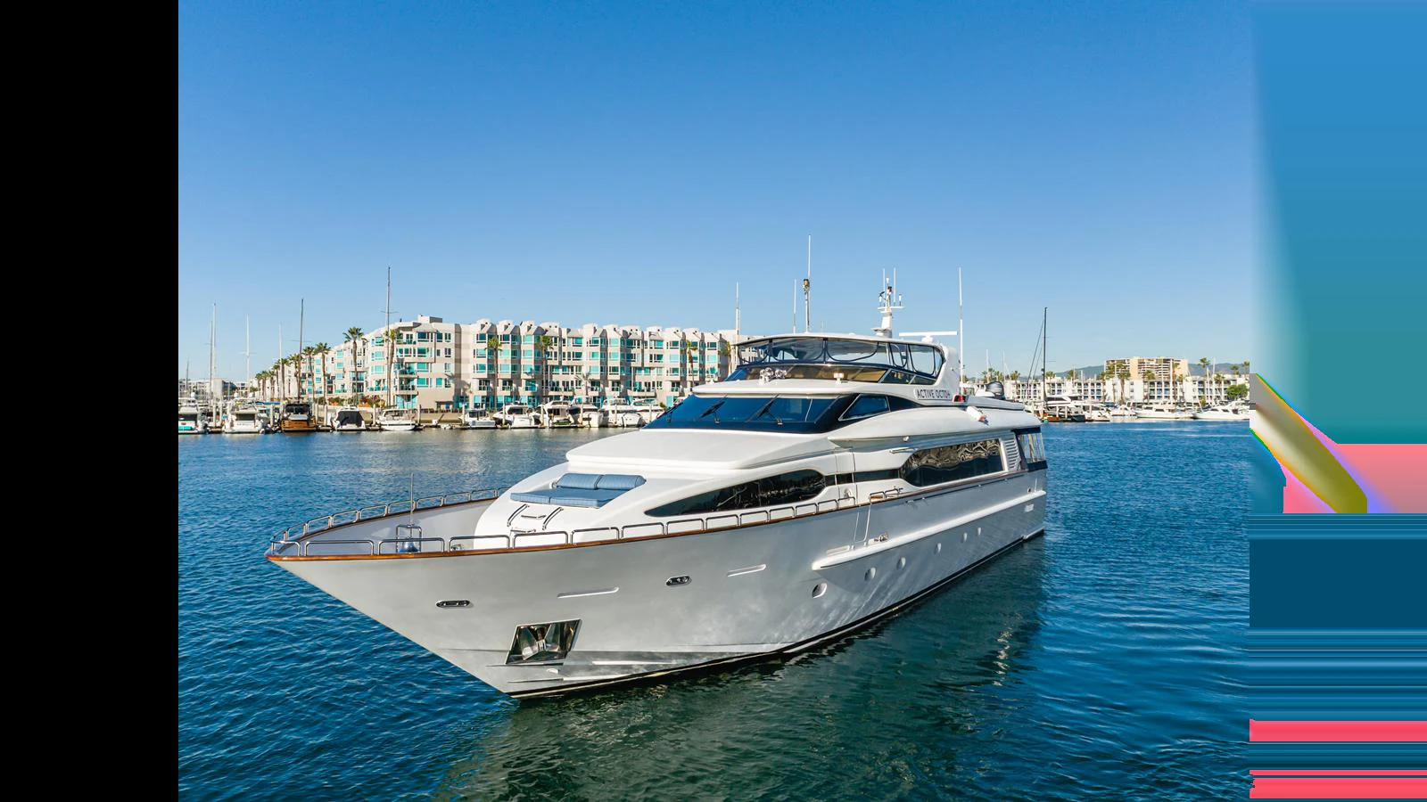 A sleek and modern yacht glides through a marina with a backdrop of waterfront buildings. aboard ACTIVE OCTO Yacht for Sale