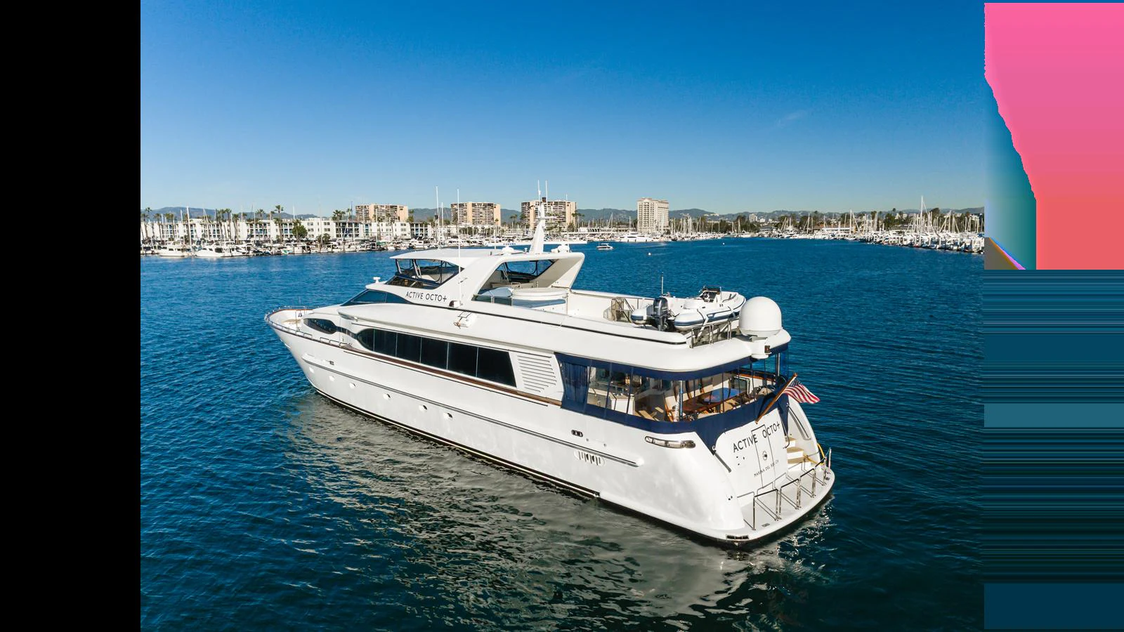 A sleek and elegant yacht cruises through a serene marina under a clear blue sky. aboard ACTIVE OCTO Yacht for Sale