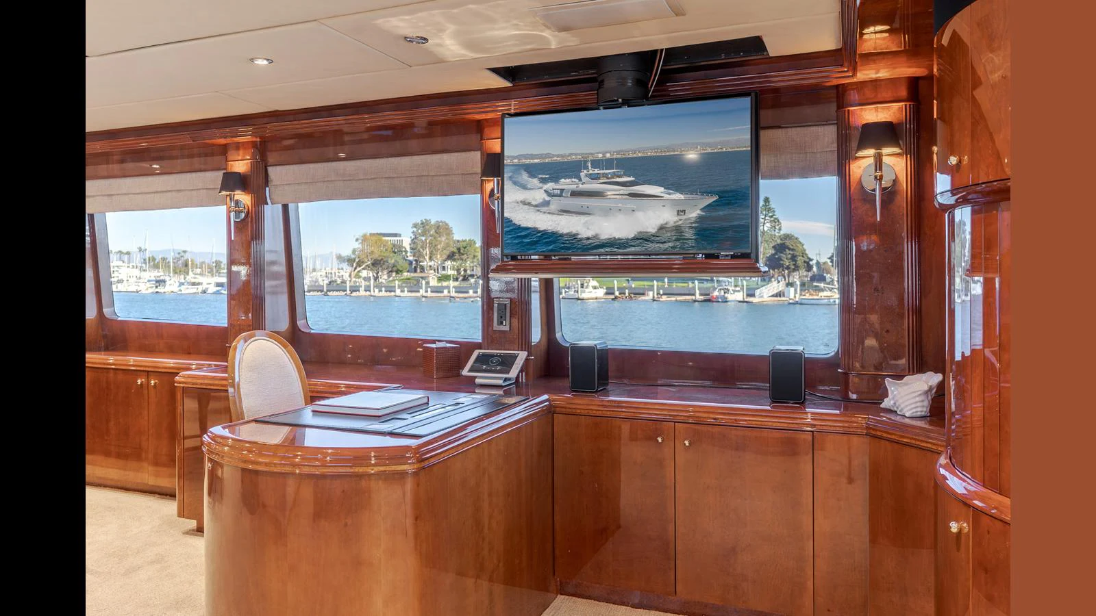 The yacht's interior features a luxurious wood-finished room with large windows offering a scenic view of the marina. aboard ACTIVE OCTO Yacht for Sale